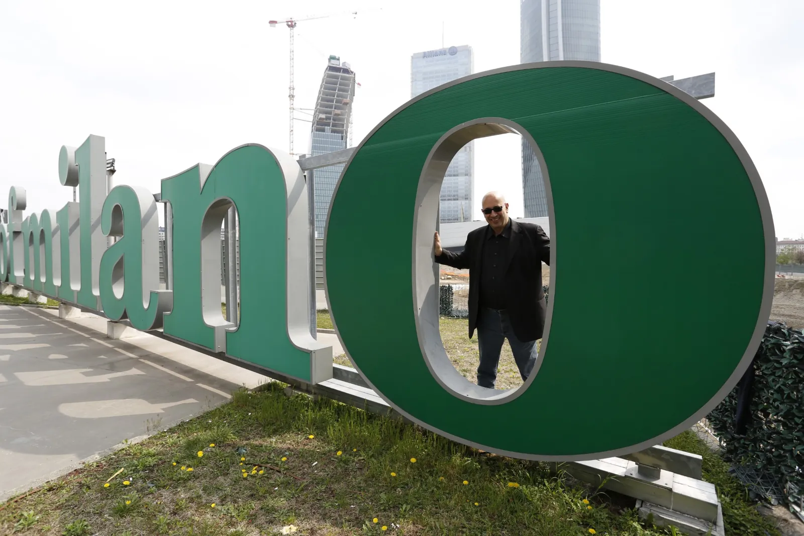 Paolo Monesi affacciato dentro la grande O verde della scritta Milano, con i grattacieli di CityLife alle spalle