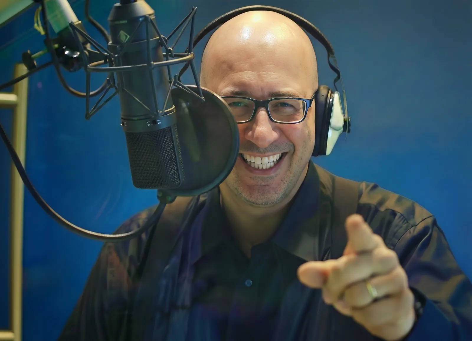 Paolo Monesi in cabina di registrazione con cuffie, ride e indica verso l'obiettivo